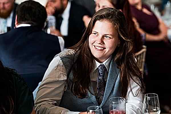 Person smiling at formal event with drinks.