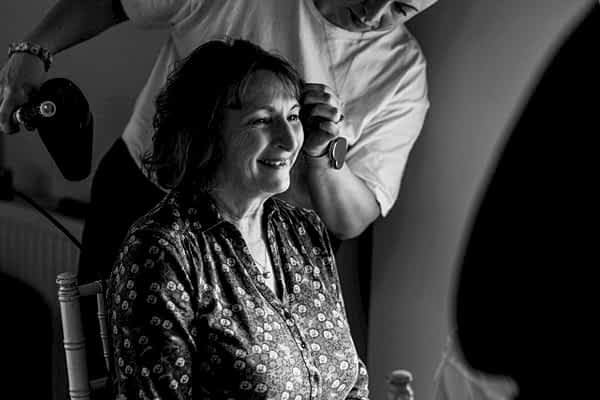 Woman getting hair styled, smiling, black and white.