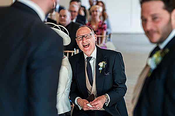 Man laughing at formal event.