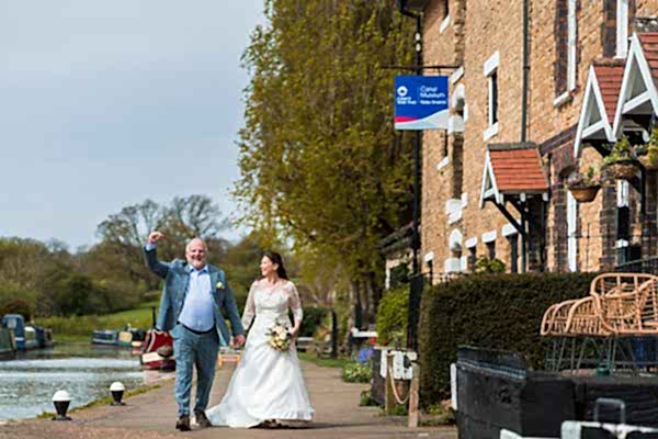 Bride and groom walking by canal museum.