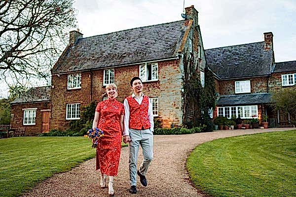 Couple in red walking by a country house.