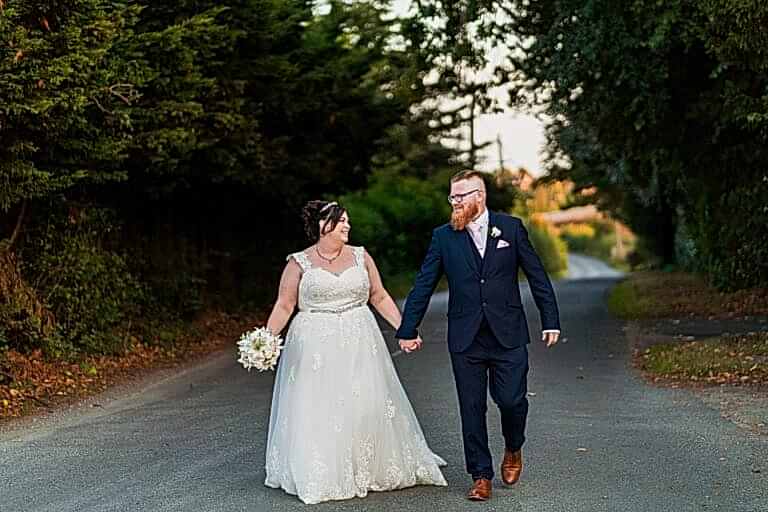 Smiling bride and groom walking hand in hand.