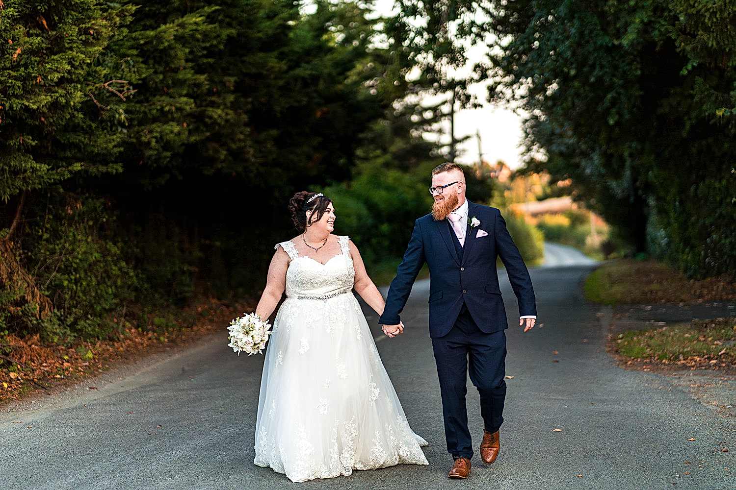 Smiling bride and groom walking hand in hand.