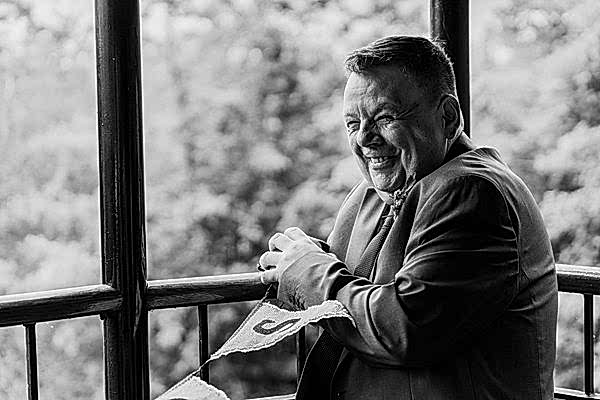 Smiling man in suit on balcony, black and white.