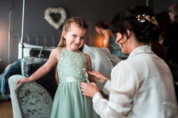 Woman adjusting girl's dress before event.