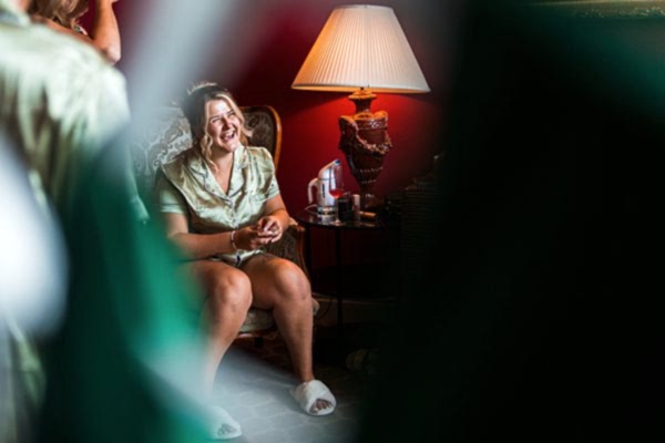 Woman laughing in cosy room with lamp.