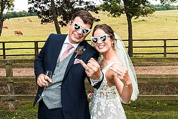 Bride and groom wearing playful sunglasses in countryside