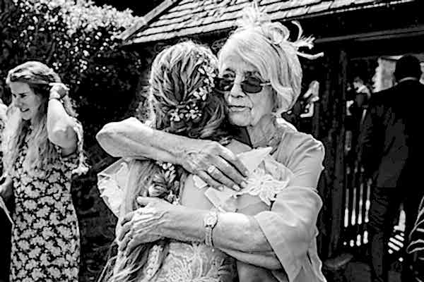 Elderly woman hugging young woman at outdoor event.