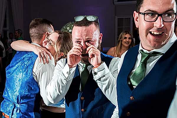Men celebrating joyfully at a wedding reception.