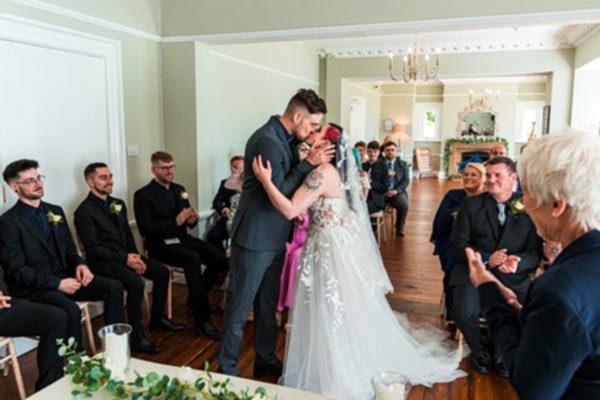 Bride and groom kiss at wedding ceremony indoors