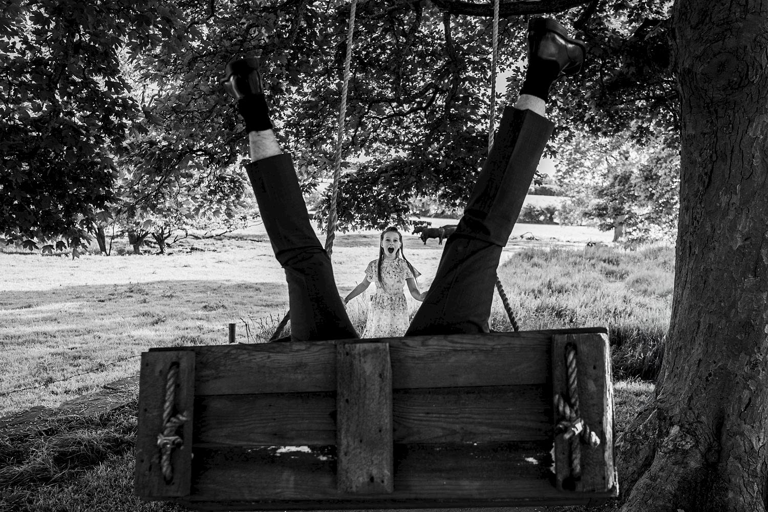 Man upside down on swing, surprised woman watching.