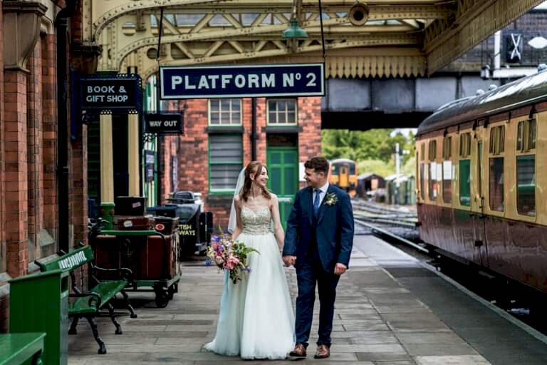 Bride and groom at vintage railway station.