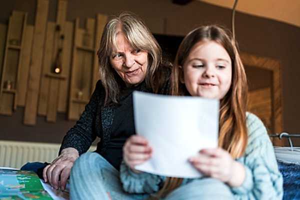 Grandmother and granddaughter reading together at home.