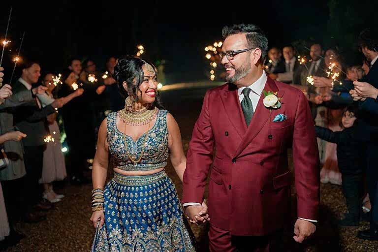 Couple at wedding with sparklers at night.