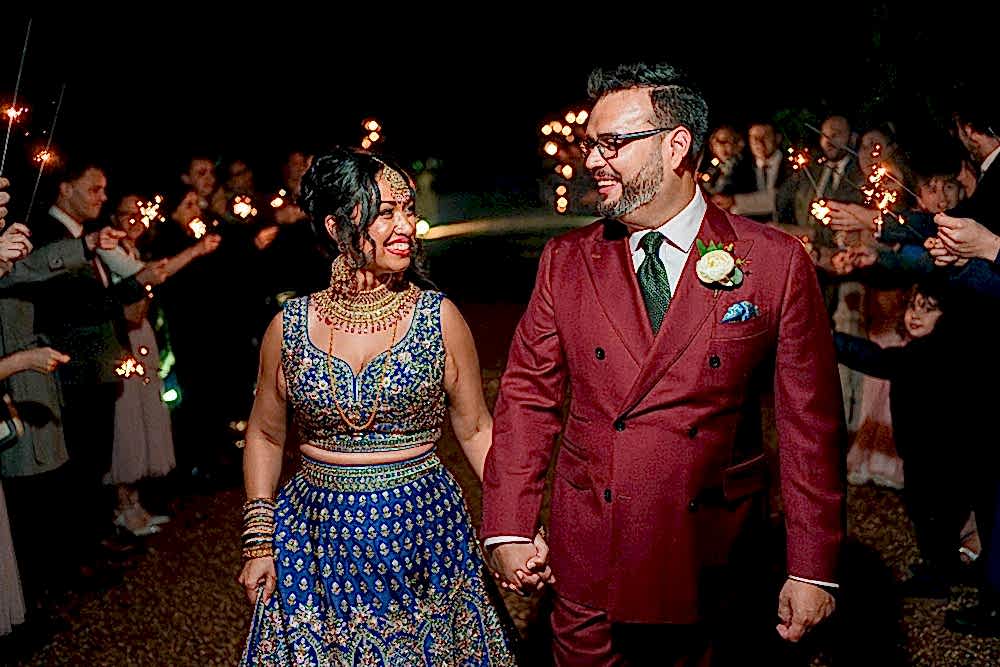 Couple at wedding with sparklers at night.