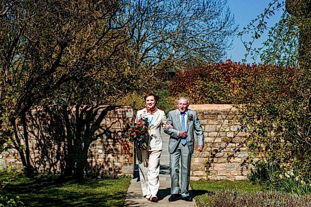 Bride and father walking in garden