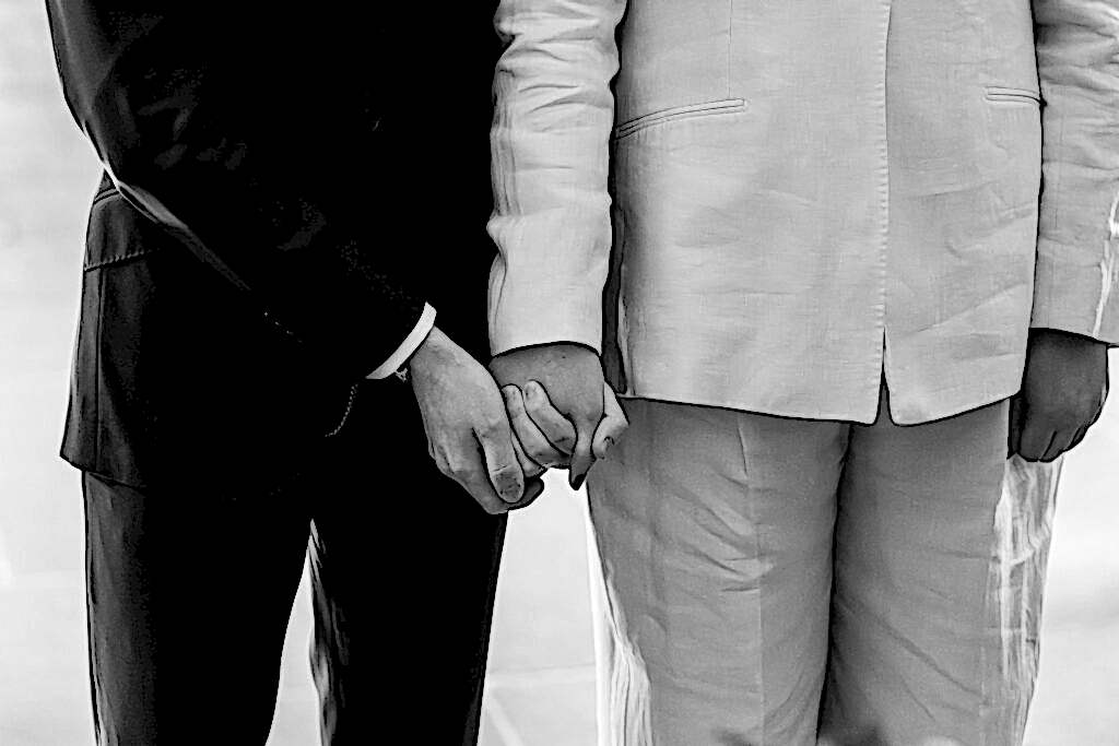 Two people in suits holding hands, close-up.