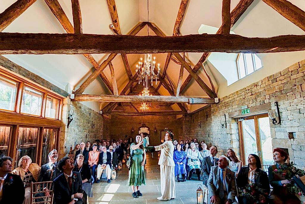 Wedding ceremony in rustic barn with guests seated.