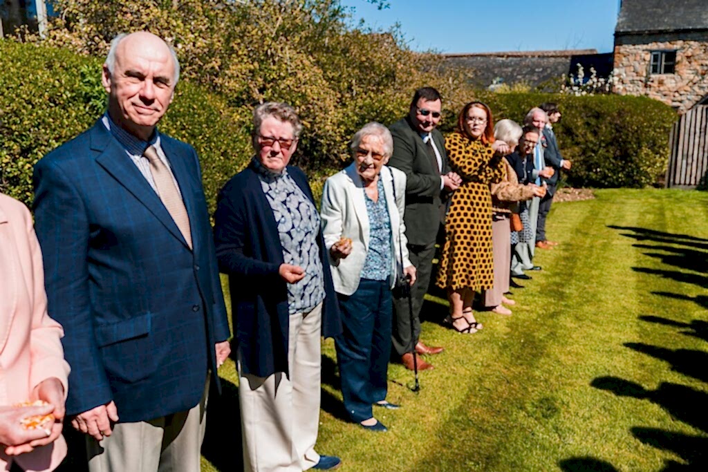 People standing in a line outside on grass.