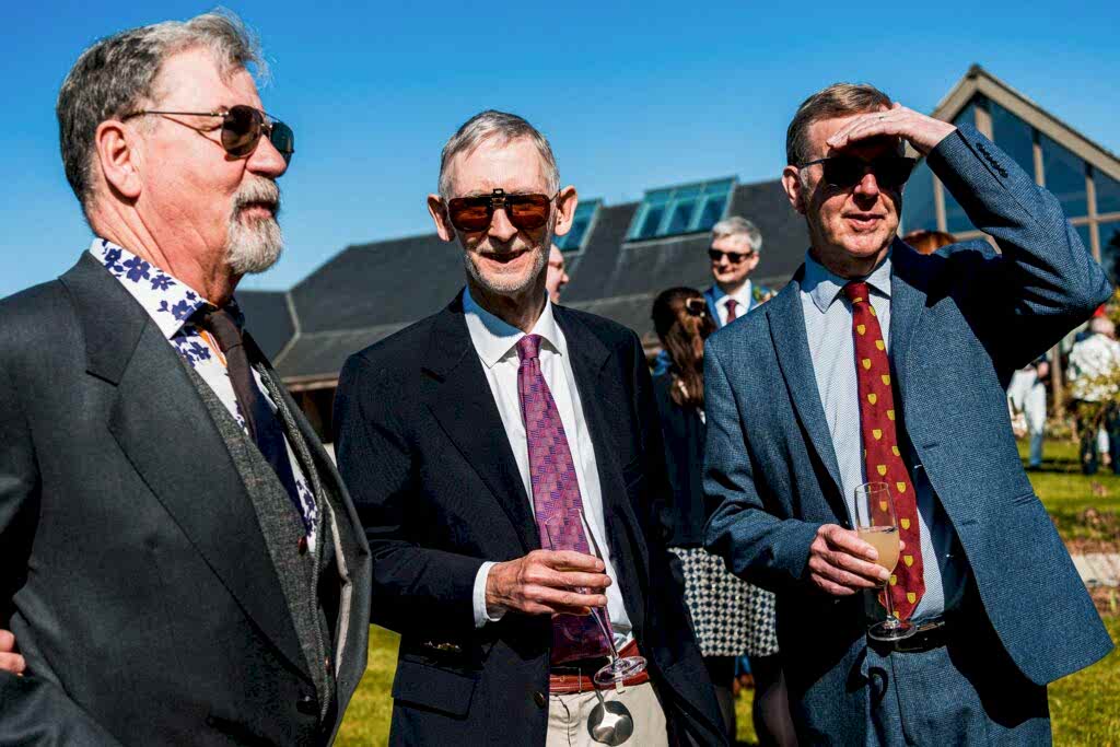 Three men in suits at outdoor event.
