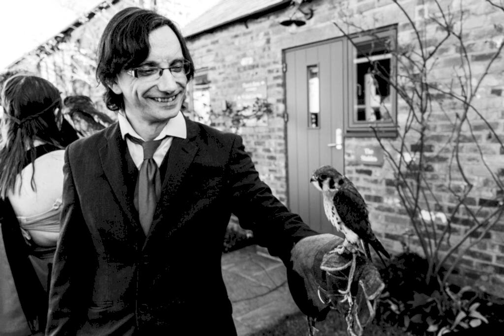 Man holding a falcon in garden ceremony.