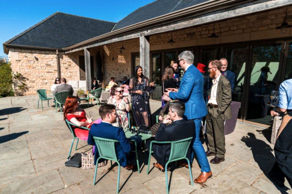 Outdoor gathering at modern stone building terrace.