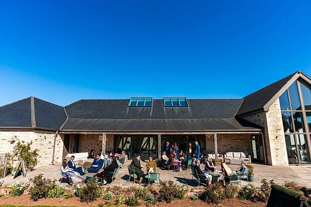 People relaxing outside modern stone building.