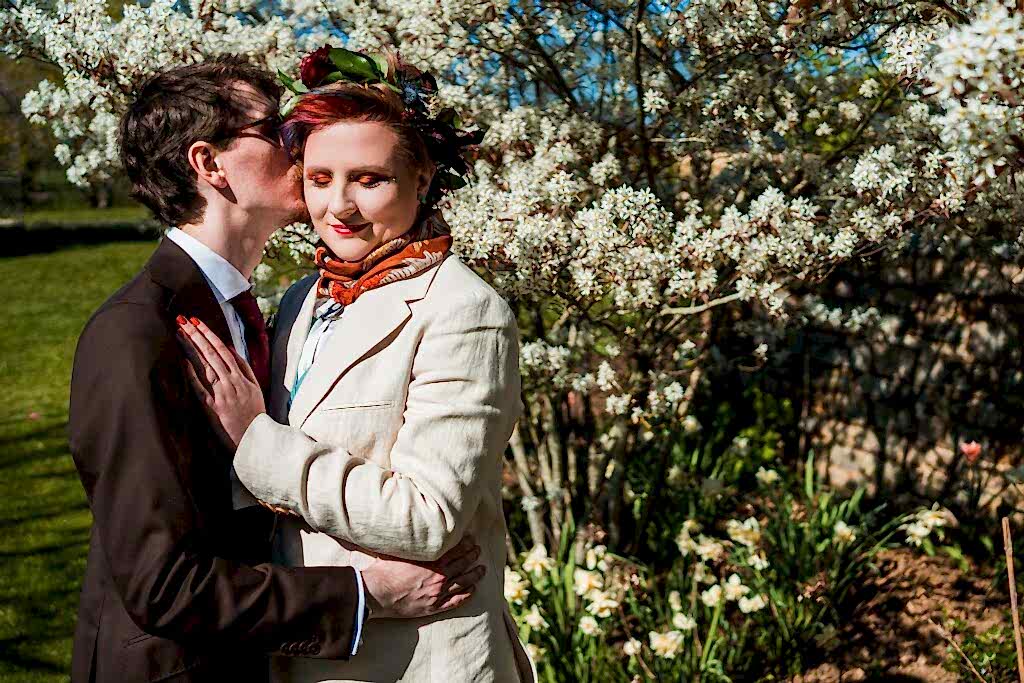 Couple embracing under blooming tree in garden.