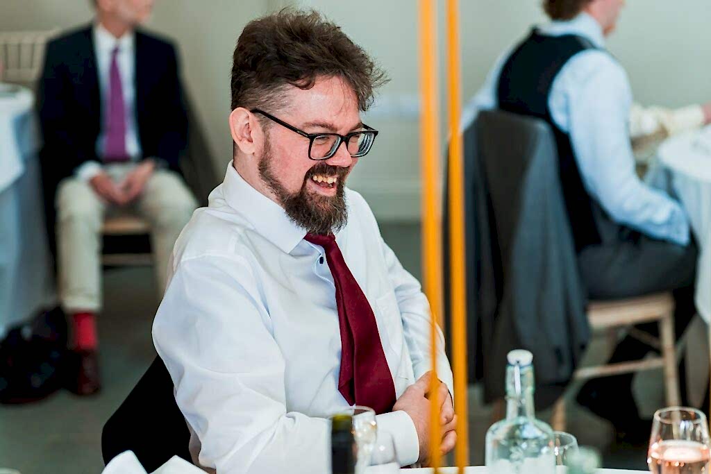 Smiling man in red tie at formal event.