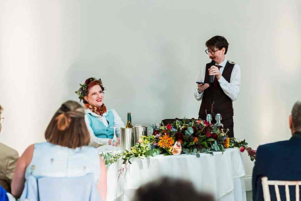 Wedding speech with guests seated, decorated table.