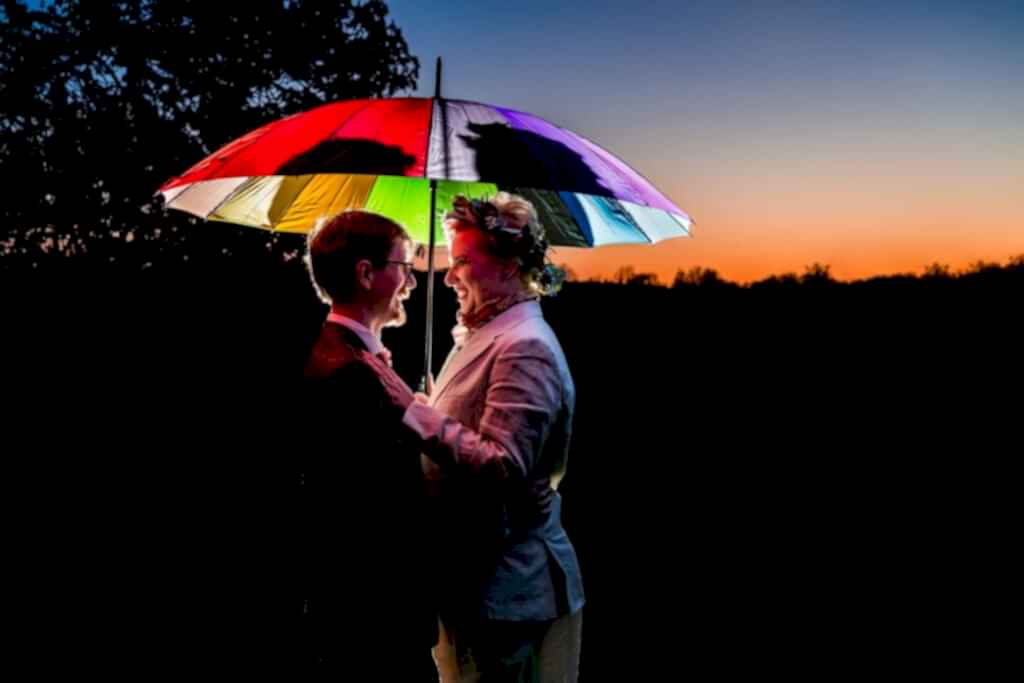 Couple under rainbow umbrella at sunset