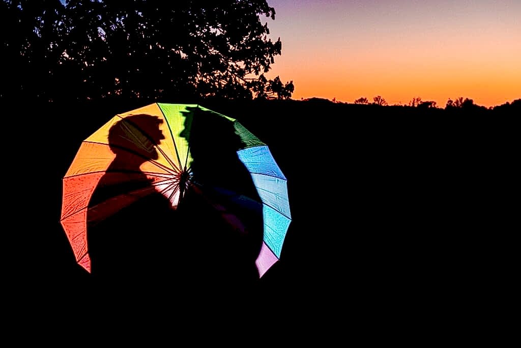 Colourful umbrella silhouetted against sunset sky