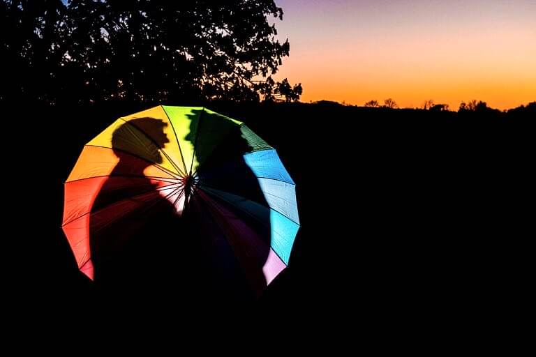 Silhouette behind a colourful umbrella at sunset.