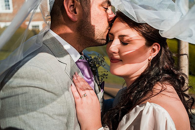 Bride and groom sharing a tender moment outdoors.