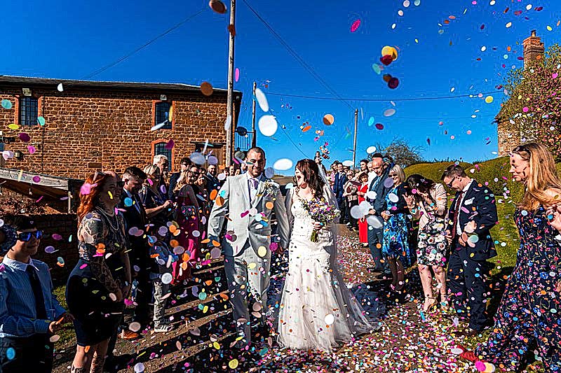 Bride and groom surrounded by colourful confetti.