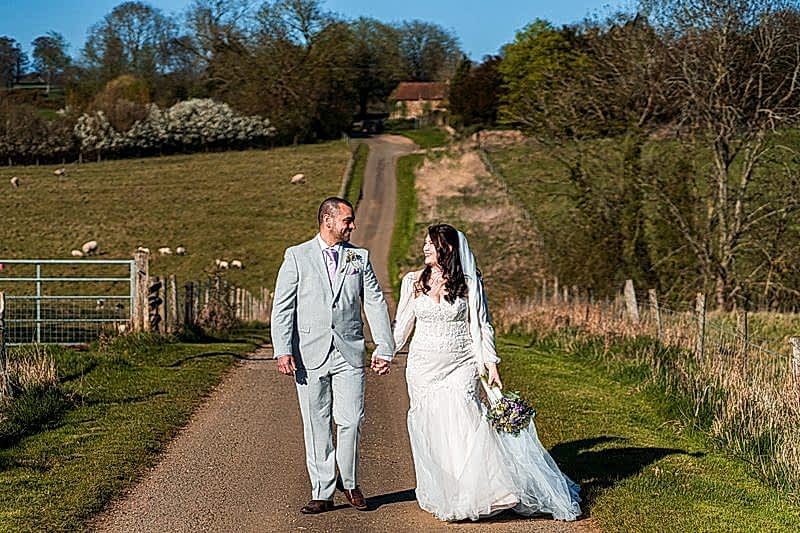 Bride and groom walk in countryside lane